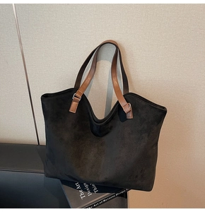 Détail du sac cabas en daim noir avec anses en cuir marron et anneaux en métal argenté