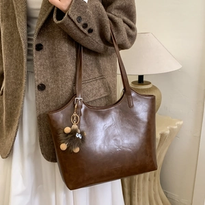 Detalle de bolso tote vintage en cuero marrón con colgante de peluche sobre modelo elegante
