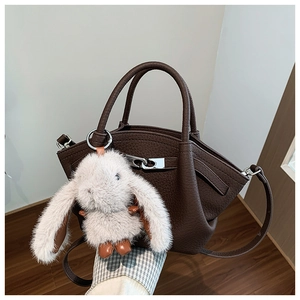Detail of dark brown lychee grain leather bucket bag with silver buckle and bunny charm
