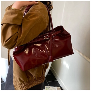 Side view of large burgundy patent leather tote bag styled on model for daily commute
