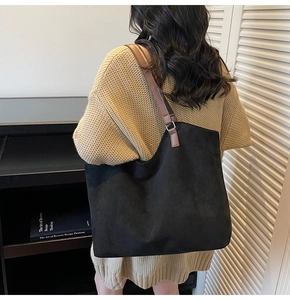 Détail du grand sac cabas en daim noir avec bandoulières en cuir marron sur l'épaule