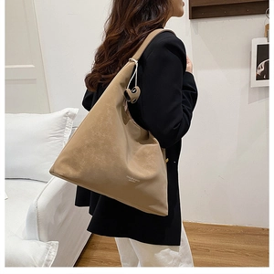 Detail view of a large camel suede shoulder bag showing texture and branding