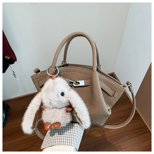 Detail of khaki pebbled leather bucket bag with silver lock and plush bunny charm