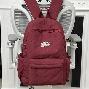 Detailansicht der weinroten Stepp-Rucksack mit Kordelzugtaschen und Logo-Etikett