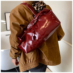 Deep red patent leather tote bag detail showing glossy finish and side buckle design