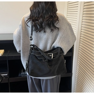 Detail of black tote bag with white contrast stitching and adjustable metal buckle strap