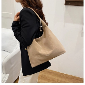 Detail der beigen Vintage Hobo-Schultertasche mit rundem Metallanhänger und Logo