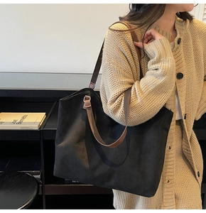 Détail d'un grand cabas noir mat avec des bretelles marron porté par un mannequin en extérieur