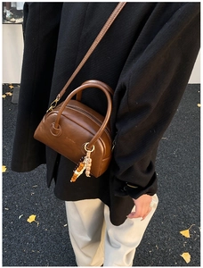 Brown leather Boston bag detail with colorful wood bead charm and crossbody strap