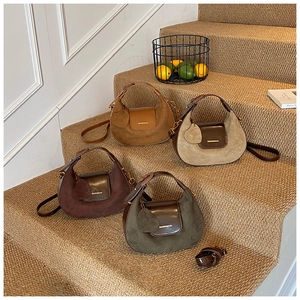 Detail of four crescent handbags in brown and green with suede texture and heart charms