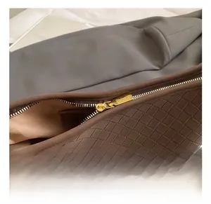 Detailed macro shot of brown woven leather texture and premium gold metal zipper hardware