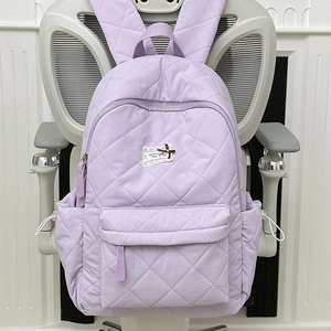 Detailansicht des lila gesteppten Rucksacks mit Karomuster und Spitzenaufnäher-Details
