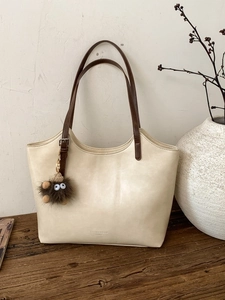 Bolso de hombro beige de cuero elegante con asas marrones y colgante de peluche
