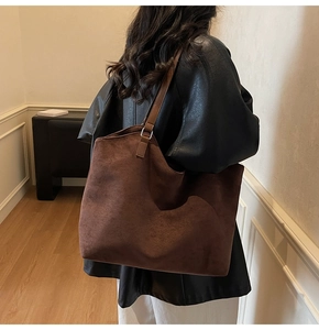 Détail du grand sac cabas en daim marron foncé avec large bandoulière en cuir sur un modèle