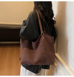 Gros plan sur un grand sac cabas en daim marron foncé avec de fines bretelles et anneaux en métal