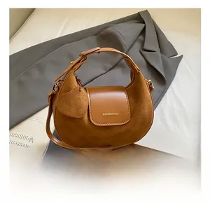 Detailed close-up of brown suede and smooth leather crescent bag with gold logo