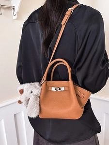 Brown litchi grain leather bucket bag with a plush elephant charm and silver twist lock