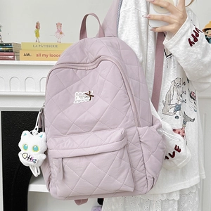 Detail eines gesteppten lavendelfarbenen Rucksacks mit Rautenmuster und Anhänger