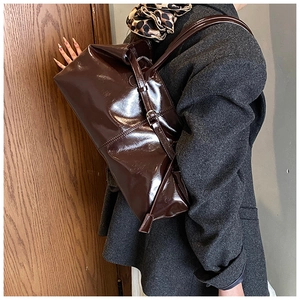 Macro detail of deep brown glossy patent leather tote bag with silver metal buckles