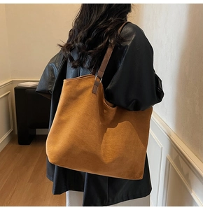 Détail de la texture en daim du sac cabas marron et de sa fine bandoulière en cuir