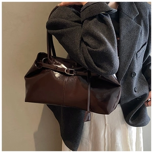 Close-up of a vintage dark brown glossy tote bag showing sleek patent leather texture