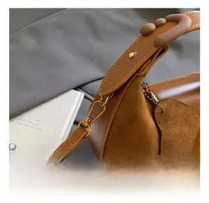 Detail of premium brown leather and suede stitching on crescent bag with gold hardware