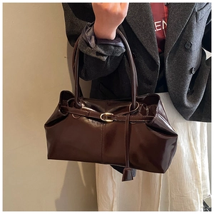 Detail of glossy dark brown leather tote bag showing retro gold buckle and texture