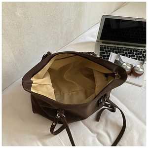 Interior detail of large brown tote bag with light yellow lining and silver metal rivets