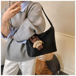 Detail of black woven leather hobo bag with a cute teddy bear charm in a lifestyle setting