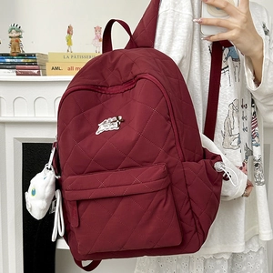 Detail des tiefroten Stepprucksacks mit Rautensteppung und vorderer Reißverschlusstasche