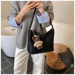 Detail of black woven tote bag featuring a cute teddy bear charm in a modern home setting