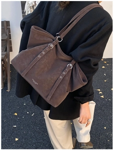 Detailed view of deep brown leather tote bag with metallic buckle straps and side logo