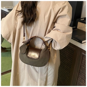 Detail of olive green suede and brown leather saddle bag with gold-tone hardware