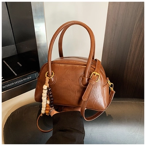 Detail of vintage brown leather bowling bag with multi-color wood bead tassel and logo