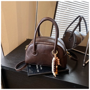 Detail of vintage brown leather bowling bag with decorative beaded keychain and double handles