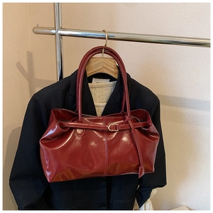 Detail of dark red glossy patent leather tote bag styled with a professional outfit