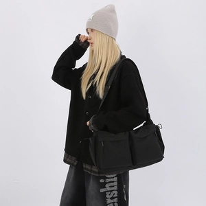 Modello maschile con borsa a tracolla nera in nylon capiente e doppie tasche frontali
