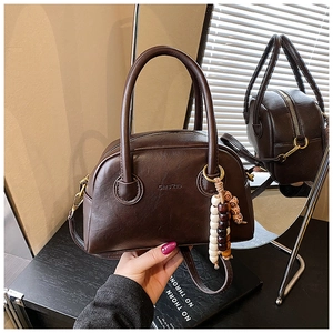 Detailed close-up of a vintage dark brown bowling bag with a beaded tassel and mirror reflection