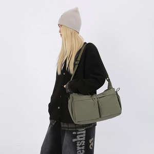 Dettaglio borsa a tracolla verde militare con doppie tasche frontali e tracolla larga