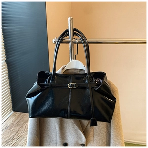 Detail of high-gloss black leather tote bag with metallic buckle on display
