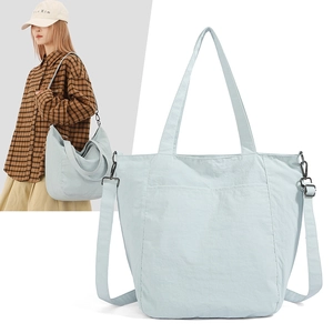 Detail view of light blue nylon tote bag with dual handles and adjustable shoulder strap