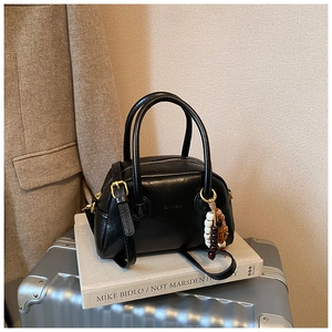 Detail of black Boston bag on metal suitcase with vintage bead charm and leather finish