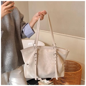 Détail du sac cabas en cuir mat blanc cassé avec œillets métalliques et sangles décoratives