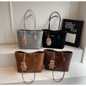 Detailed display of four textured tote bags in gray, black, and brown with plush bear charms