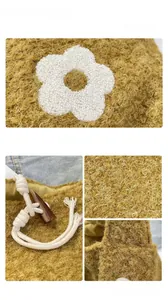 Detailed macro view of wool tote bag featuring white floral applique and horn button closure
