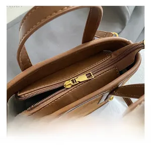 Detailed top view of brown tote bag featuring golden zipper and premium suede finish
