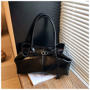 Detail of black glossy faux leather shoulder bag with buckle and decorative tassel