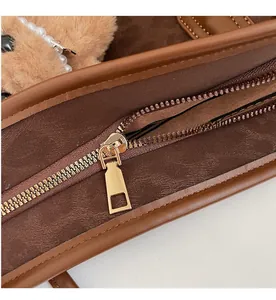 Detail of gold metal zipper on brown textured leather tote with pearl charm decoration