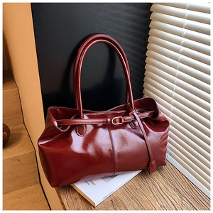 Close-up of high-gloss burgundy leather texture and gold buckle on retro shoulder bag
