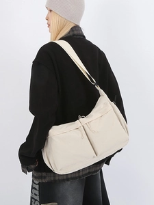 Sac fourre-tout en nylon beige avec poches frontales et sangle ajustable porté par modèle
